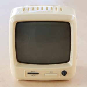 A small cream vintage TV set, switched off, on pale oak