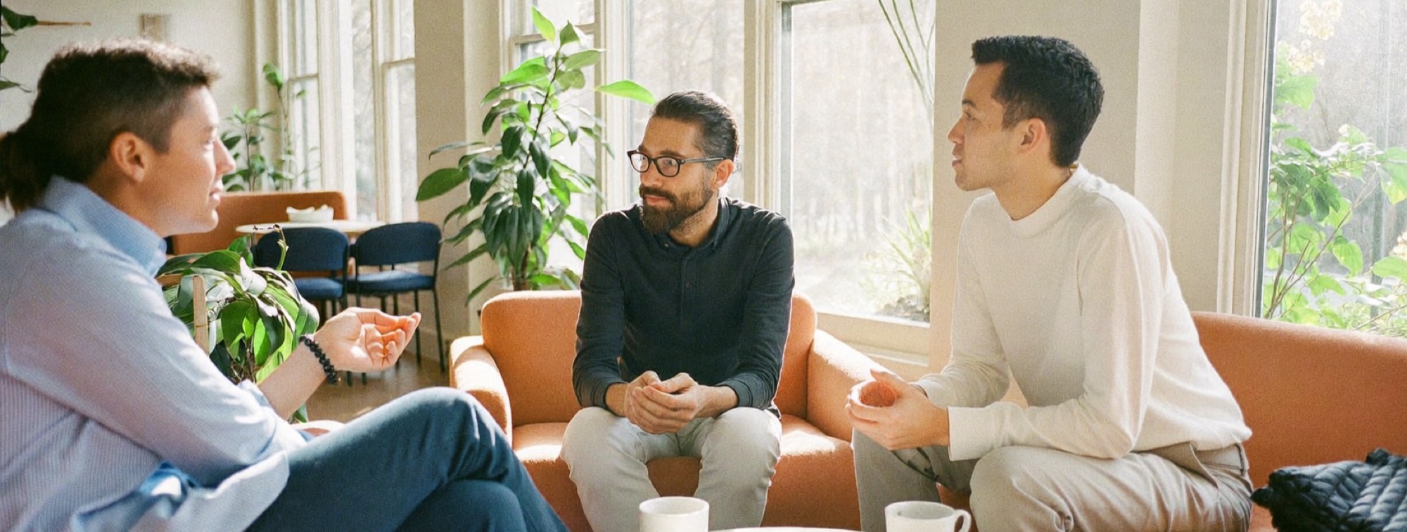 A creator listening to two of his viewers over coffee in a bright café lounge