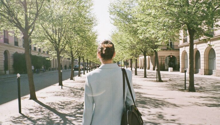 A founder heading out on a bright morning, seen from behind on a tree-lined street