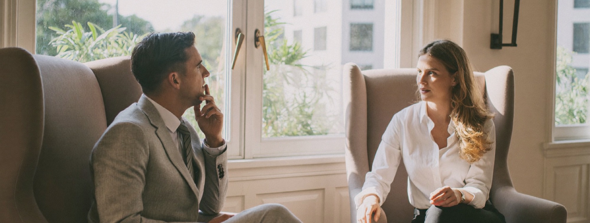 A high-ticket offer in practice: a consultant and a founder client in conversation in a bright hotel lounge