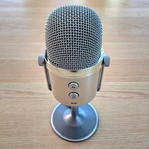A classic silver broadcast microphone on pale oak