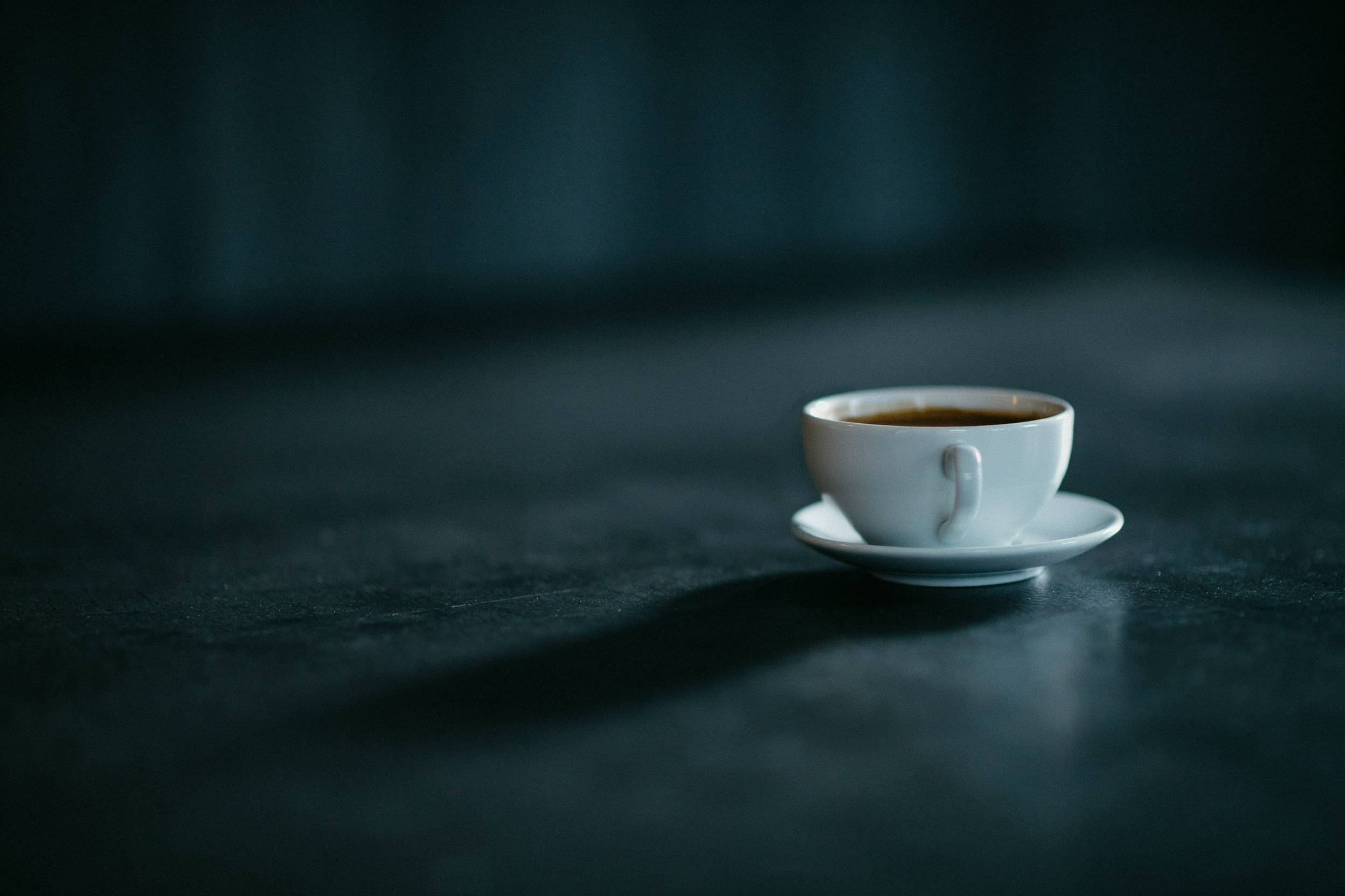 An espresso cup casting a long shadow, showing caffeine borrowed from tomorrow