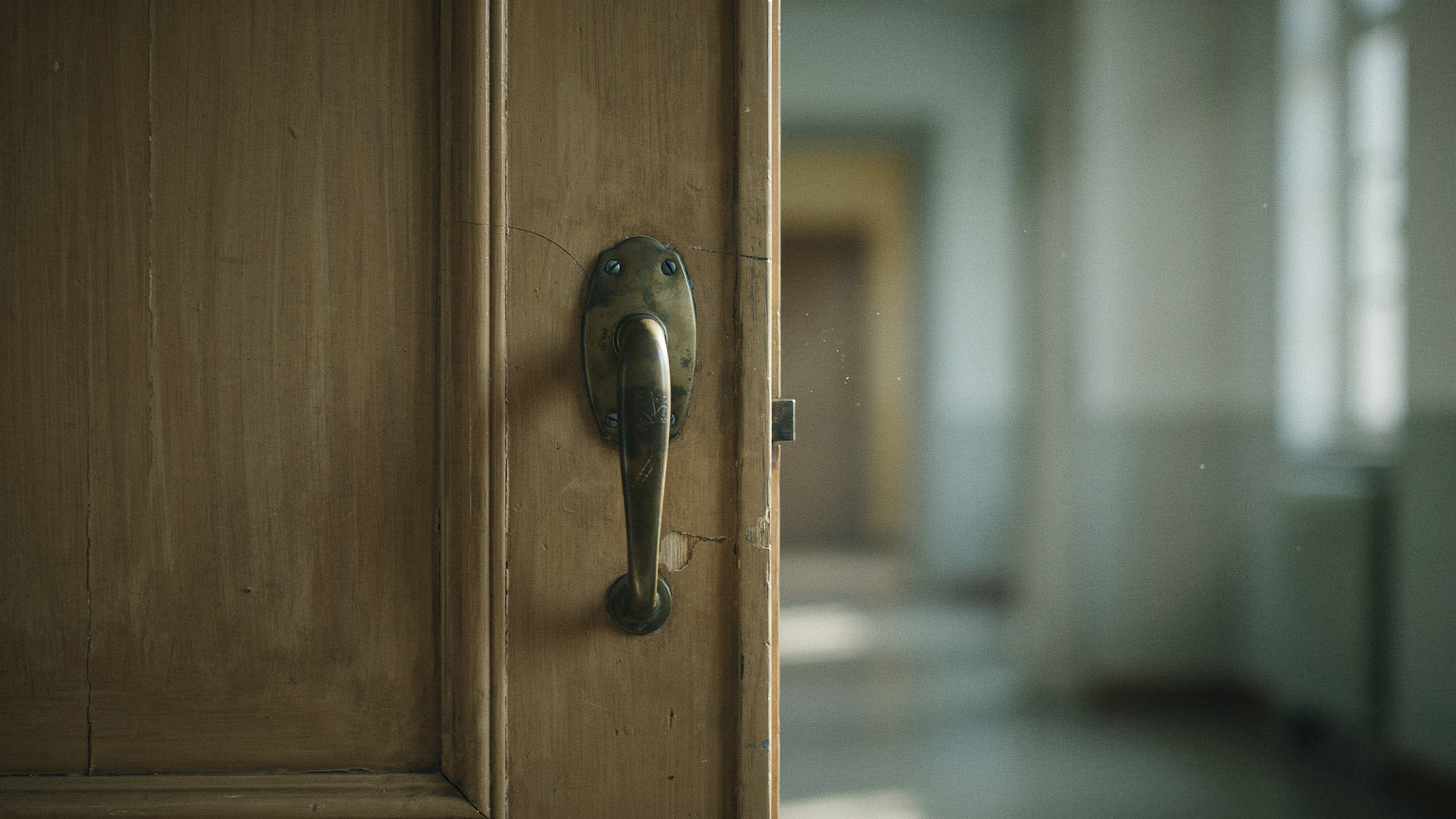 A worn brass door handle on an old wooden door, illustrating decisions that look reversible