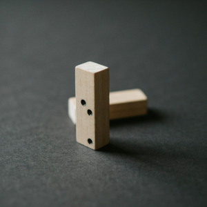A single domino standing on a dark surface, the first step in a chain of consequences