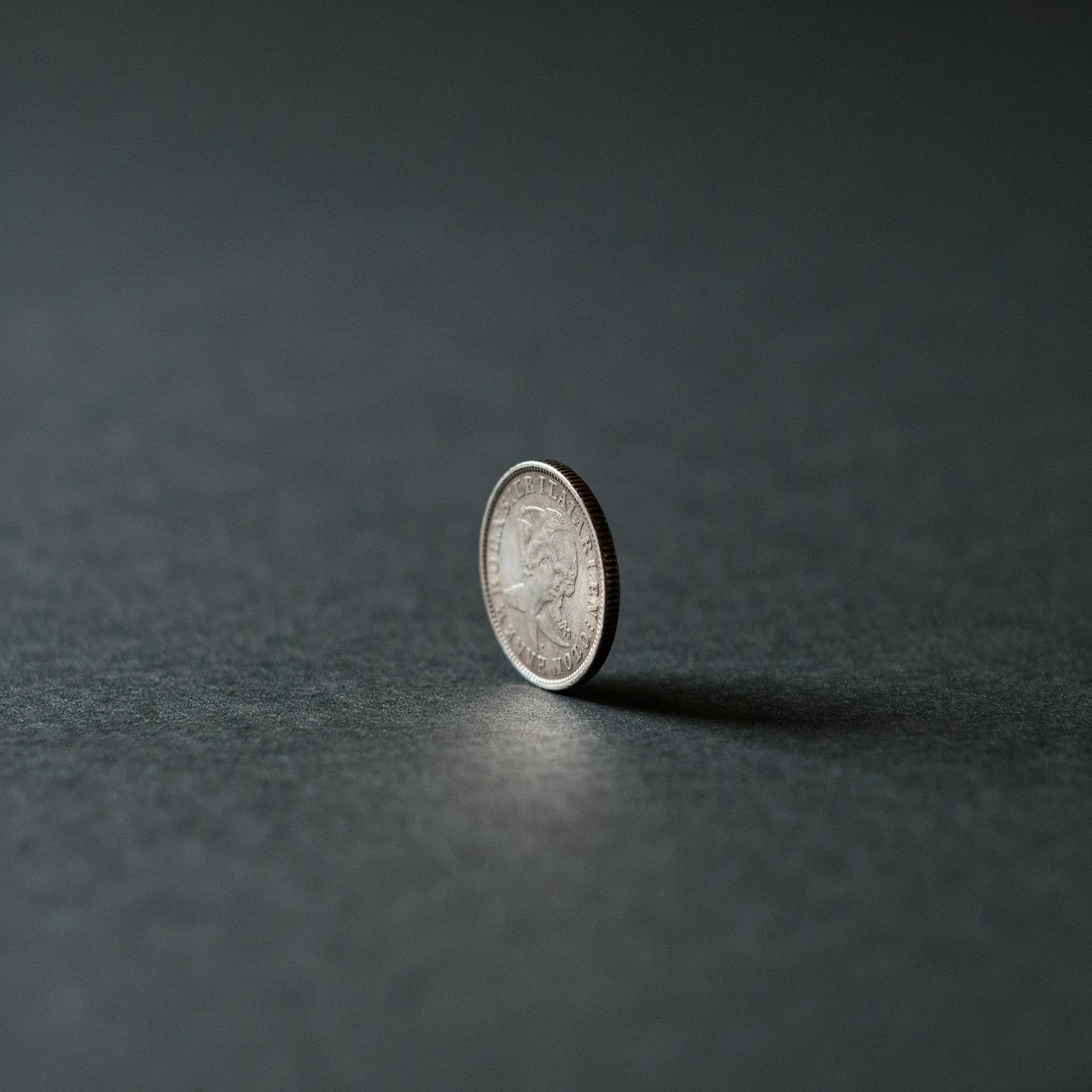 A single coin standing on edge, the fee that compounds quietly against a portfolio