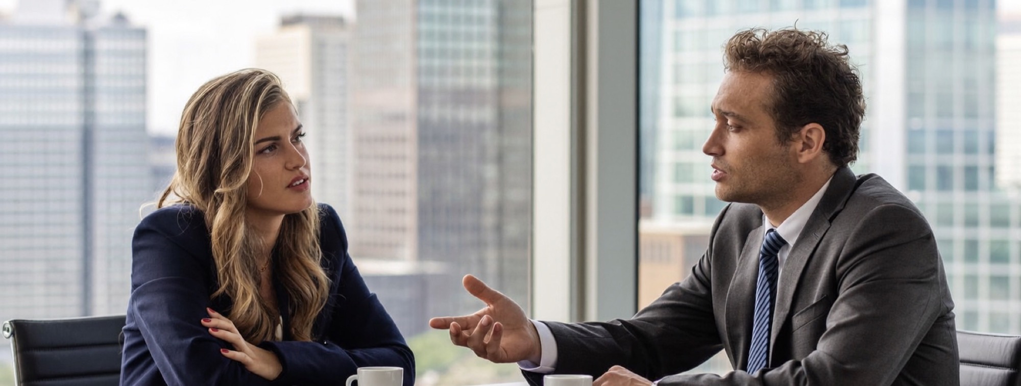 A sceptical client with arms folded while an advisor gestures across the table