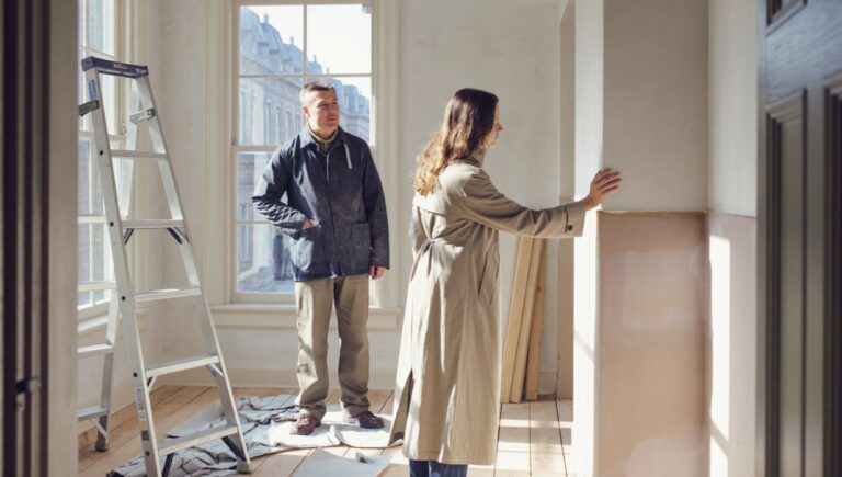 Dealing with difficult clients: a homeowner inspecting the plasterwork while her contractor watches