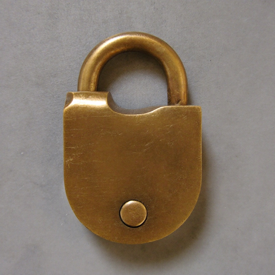 A heavy brass padlock, closed, on grey stone