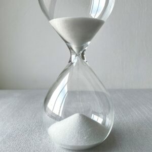 a large glass hourglass with white sand on pale linen