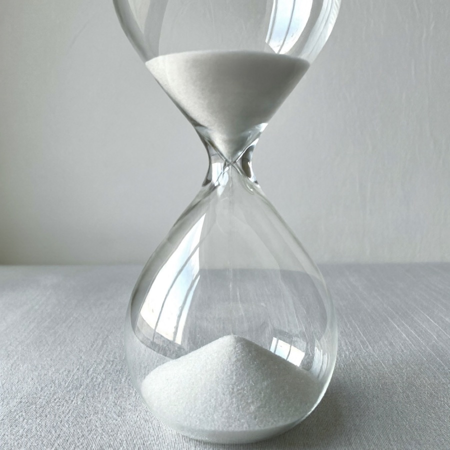 a large glass hourglass with white sand on pale linen