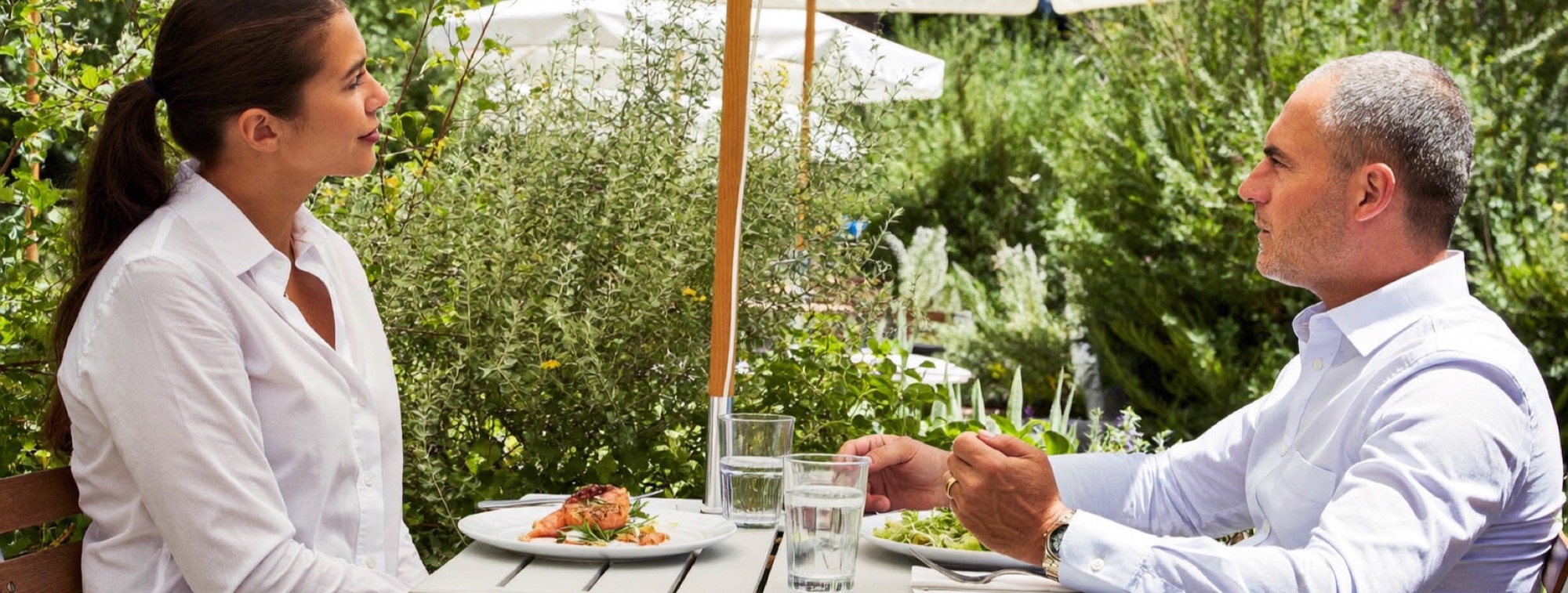 Two colleagues over a lunch of grilled salmon and salad on a sunny terrace