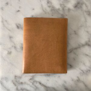 A closed tan leather wallet on white marble