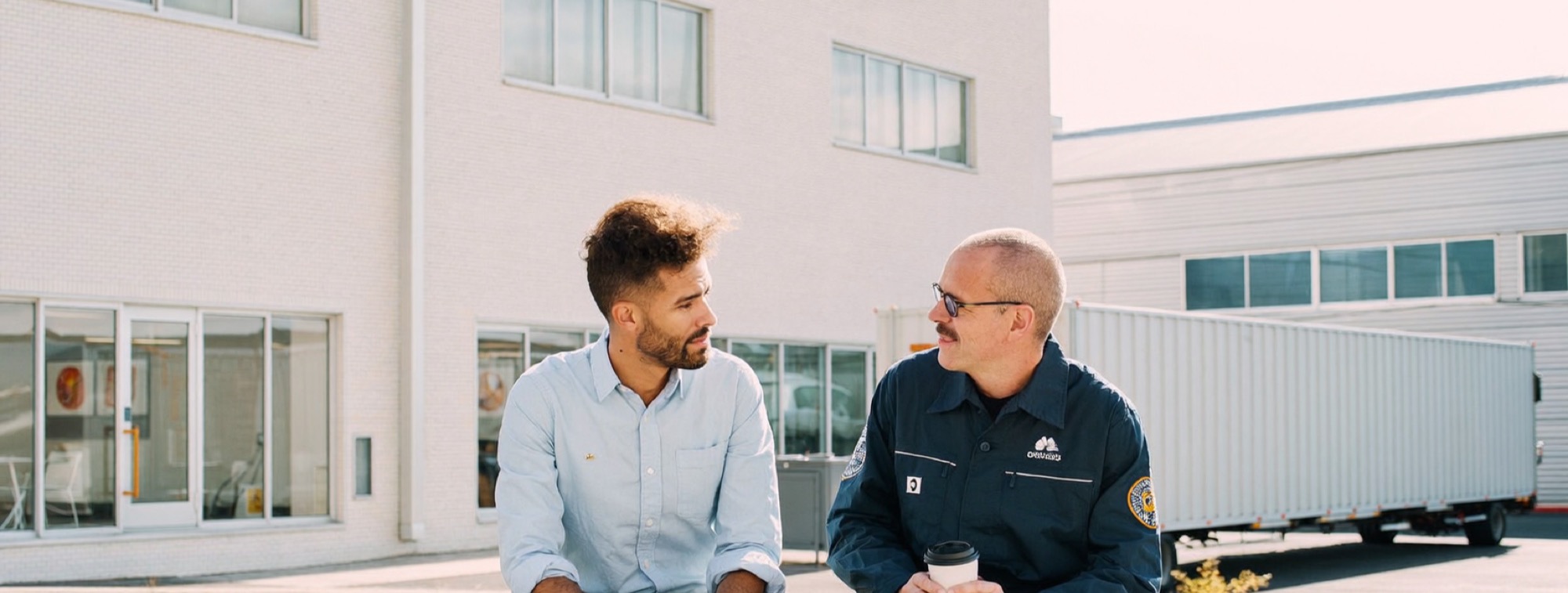 A solo business owner with an industrial client on a bench outside the plant