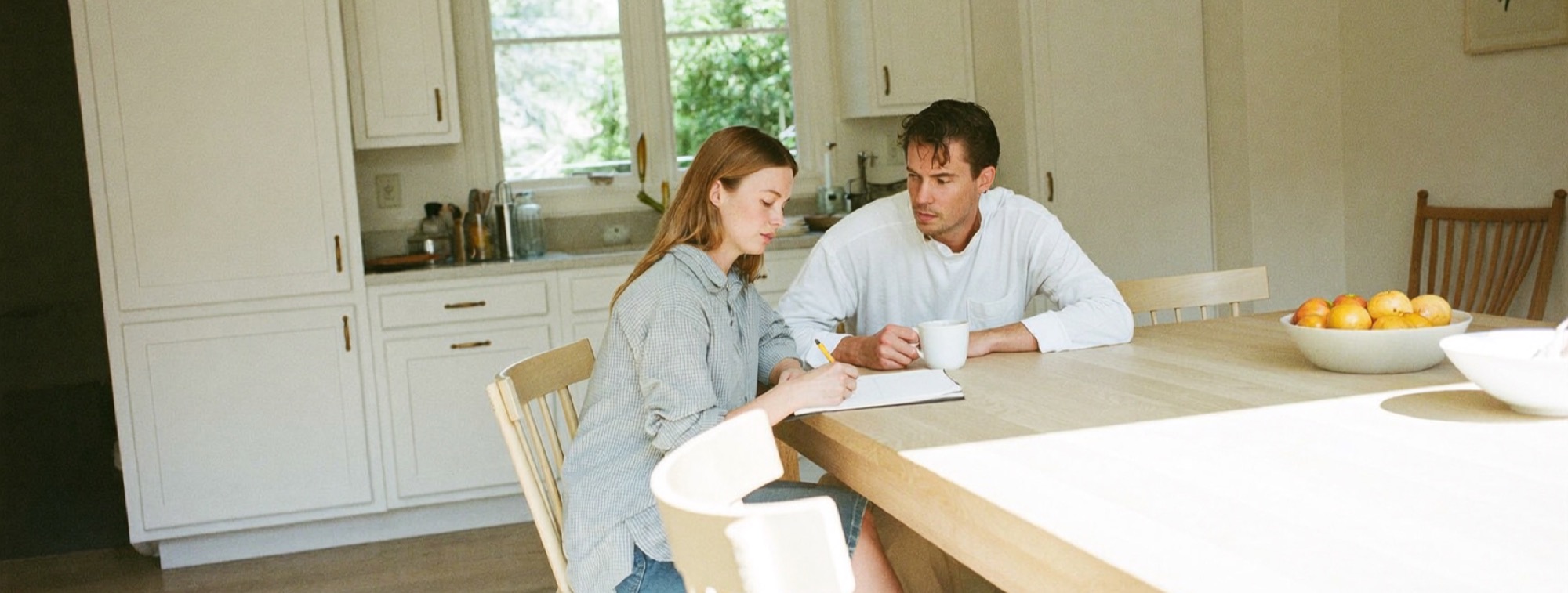 A couple at their kitchen table writing down the monthly floor their income has to cover