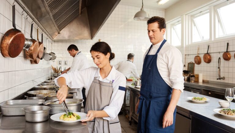 How to delegate: a head chef stepping back while his sous chef plates a dish at the pass