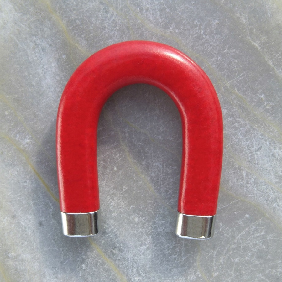 How to get your first clients: a red horseshoe magnet on pale grey stone