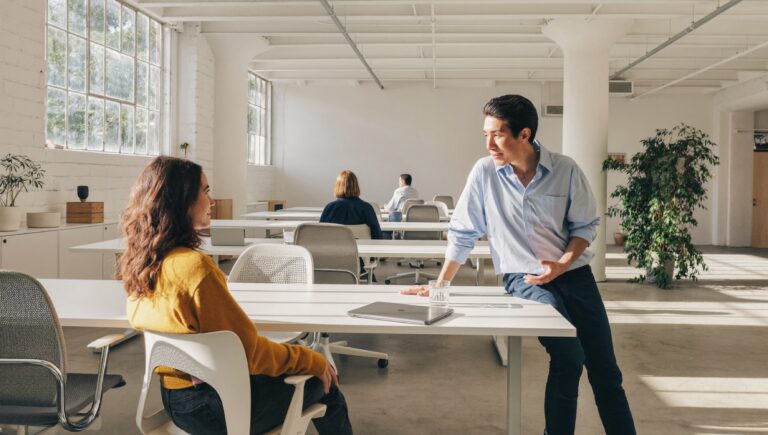 How to say no at work: an engineer turning her chair to talk with a product manager on a bright software company floor