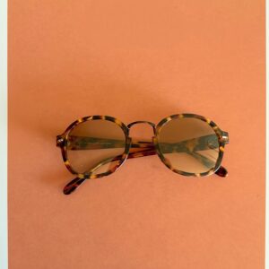 Folded tortoiseshell sunglasses on warm terracotta