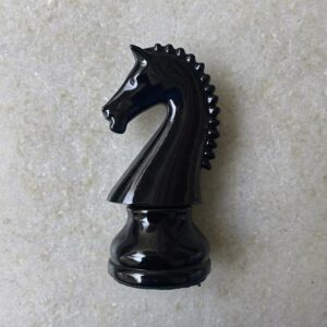 A black chess knight on pale grey stone