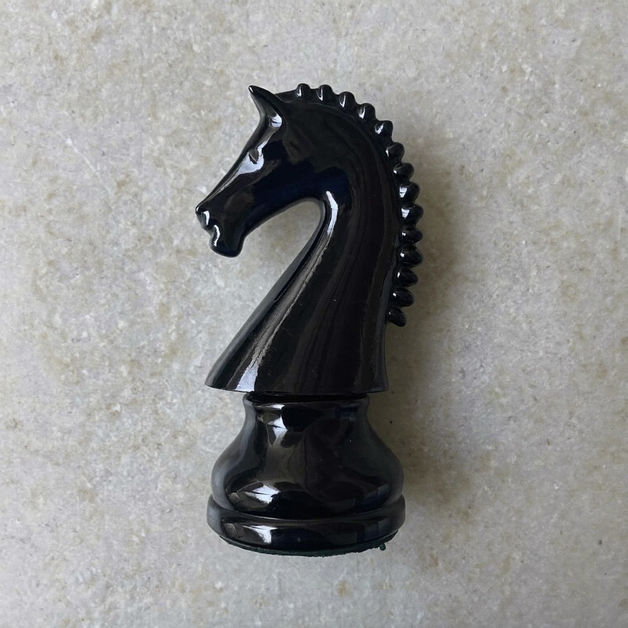 A black chess knight on pale grey stone