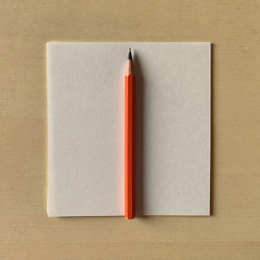 A pencil resting on blank paper, the shortest distance between a thought and a sentence