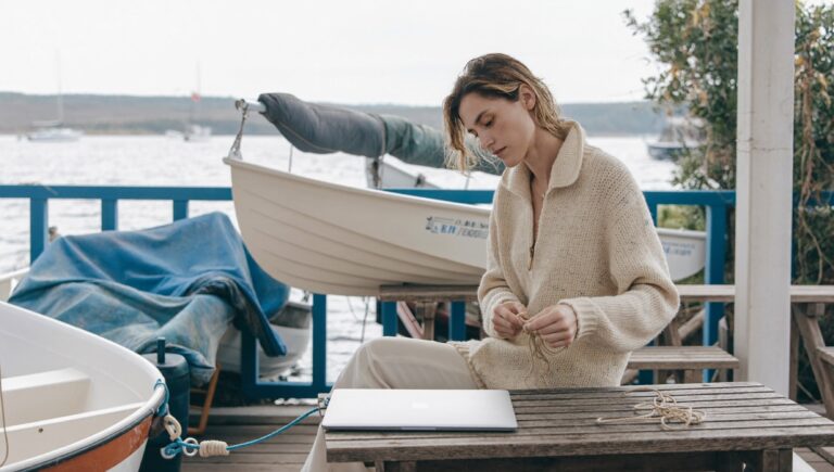 A woman on a sailing club terrace with her laptop closed, one of the work life balance examples