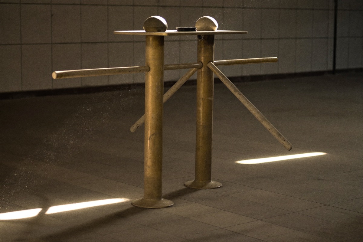 An empty turnstile in a tiled hall, paying for entry rather than for outcome