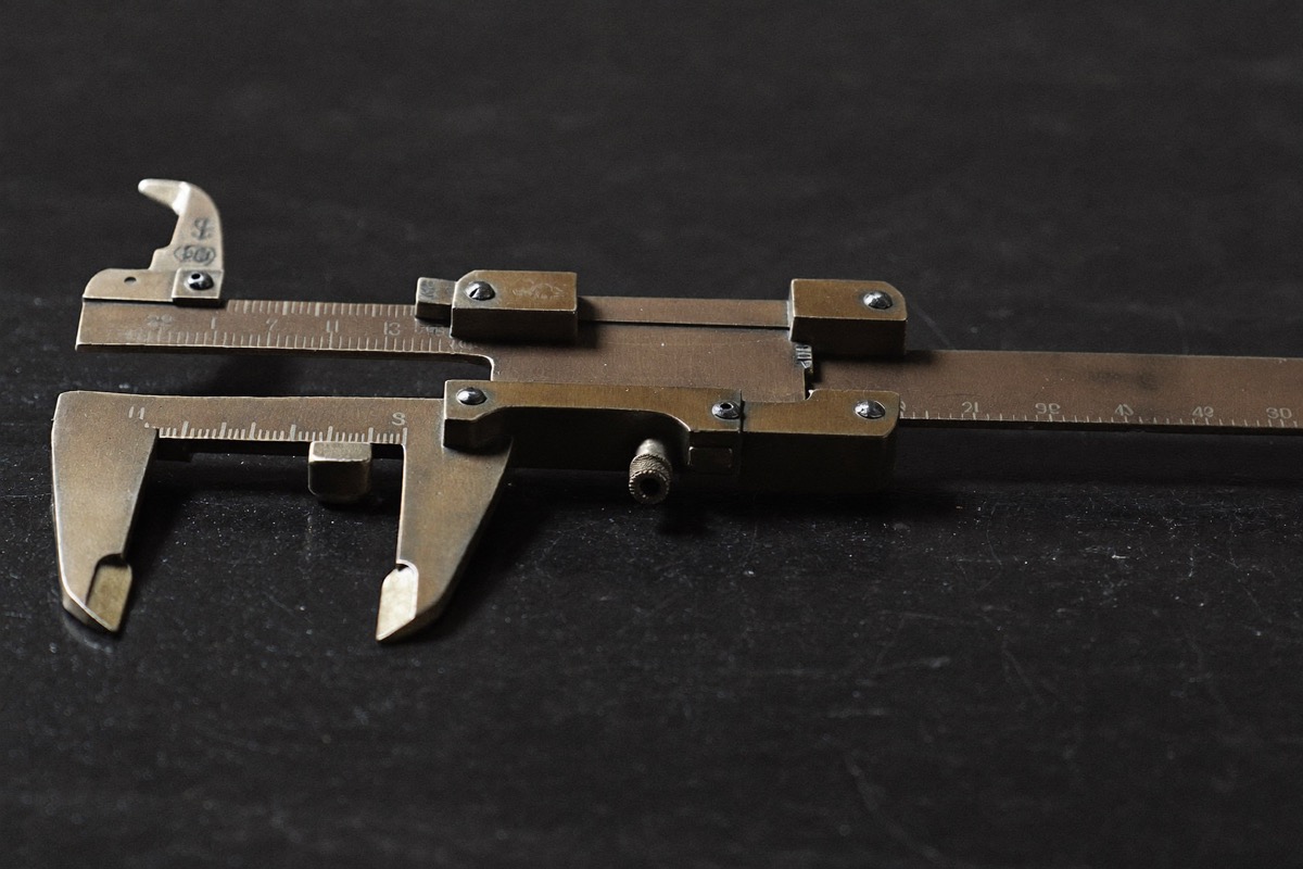 A brass caliper on a dark surface, the same data measured two different ways