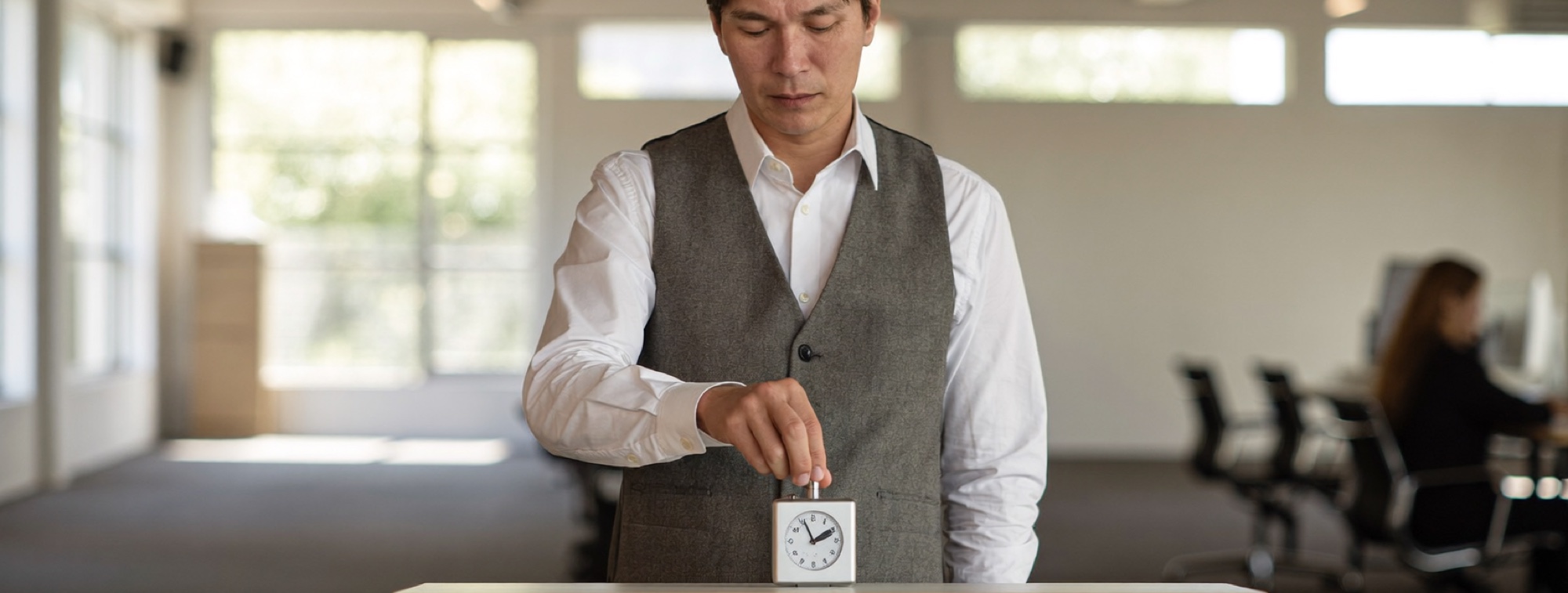A man at a standing desk in an open-plan office starting a timer