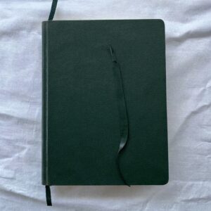 A closed green leather notebook with its ribbon marker left halfway through