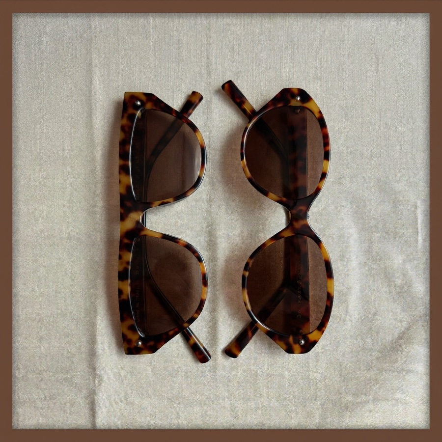 A pair of folded tortoiseshell sunglasses on pale linen