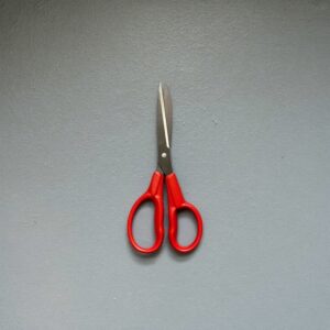 A closed pair of red-handled scissors, the tool for cutting an open decision short