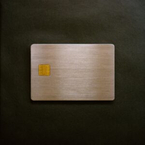 A heavy metal credit card with a gold chip, lying on dark leather