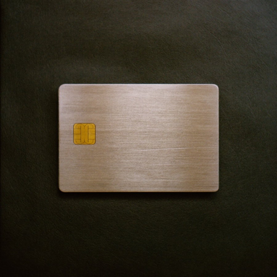 A heavy metal credit card with a gold chip, lying on dark leather