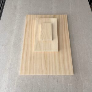 Three plain wooden blocks stacked on pale grey stone