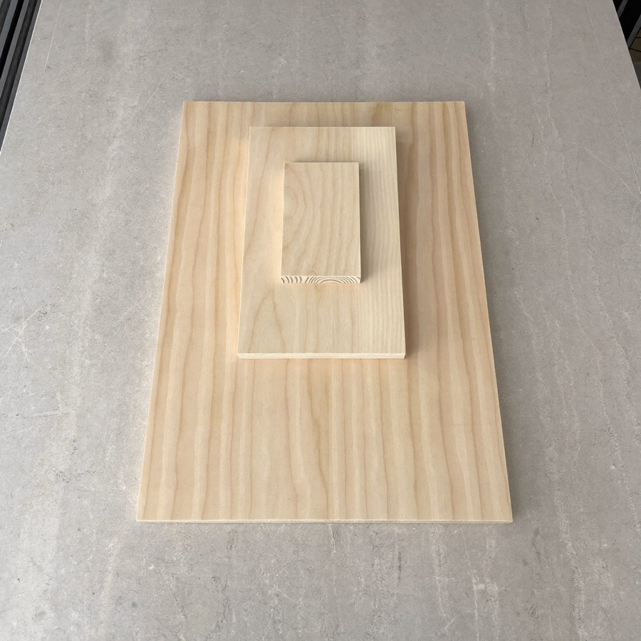 Three plain wooden blocks stacked on pale grey stone