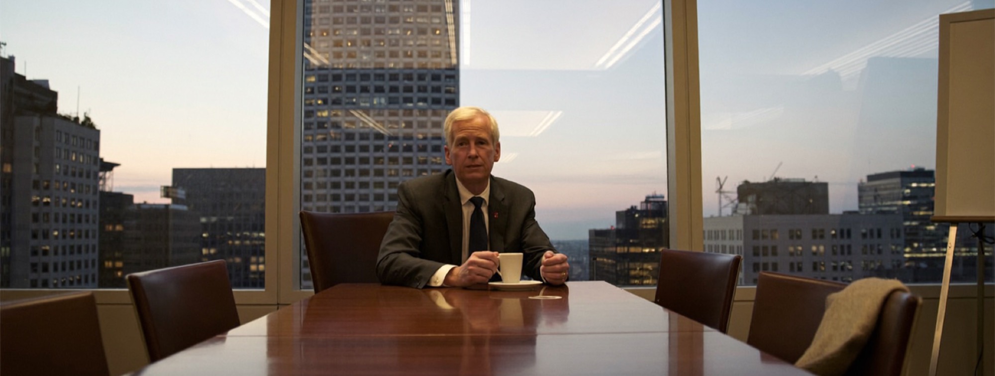An executive alone at the boardroom table at dusk after the meeting