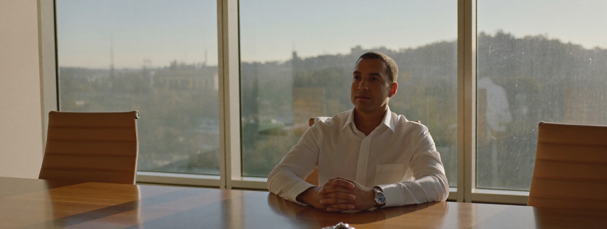 A man at a table at first light with his wristwatch set in front of him