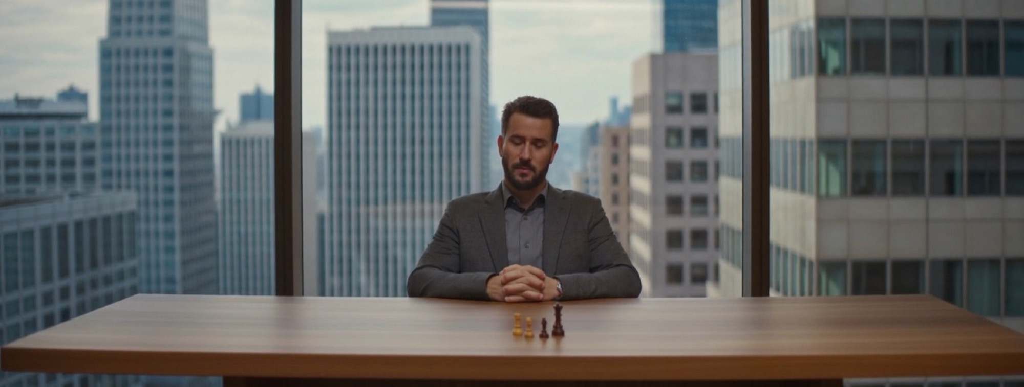 A man looking at a single chess piece set on a meeting table