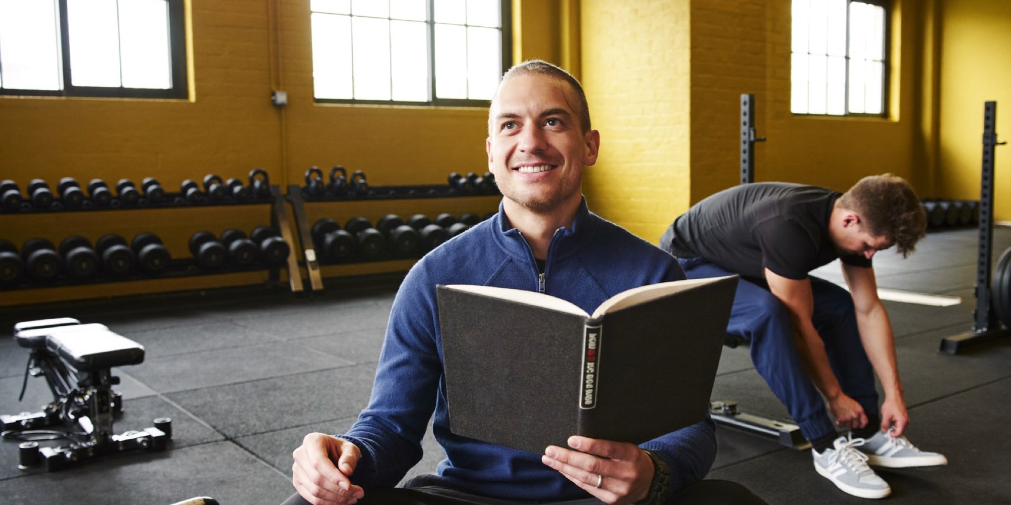 A gym owner reading between sessions, the business Alex Hormozi's books grew out of
