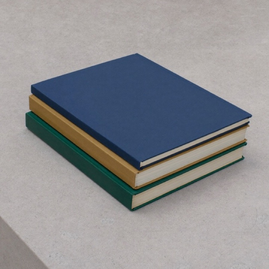 A stack of three hardbacks, the Alex Hormozi books in reading order