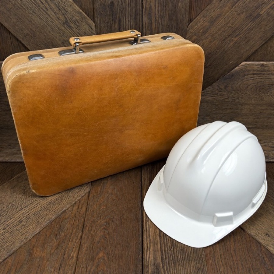 An old briefcase beside a new hard hat, a career change at 50