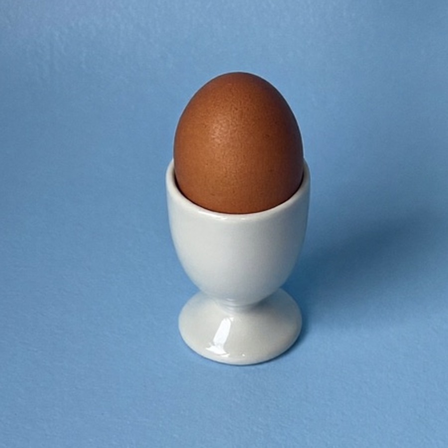 A boiled egg in an egg cup, breakfast for someone learning how to become a morning person