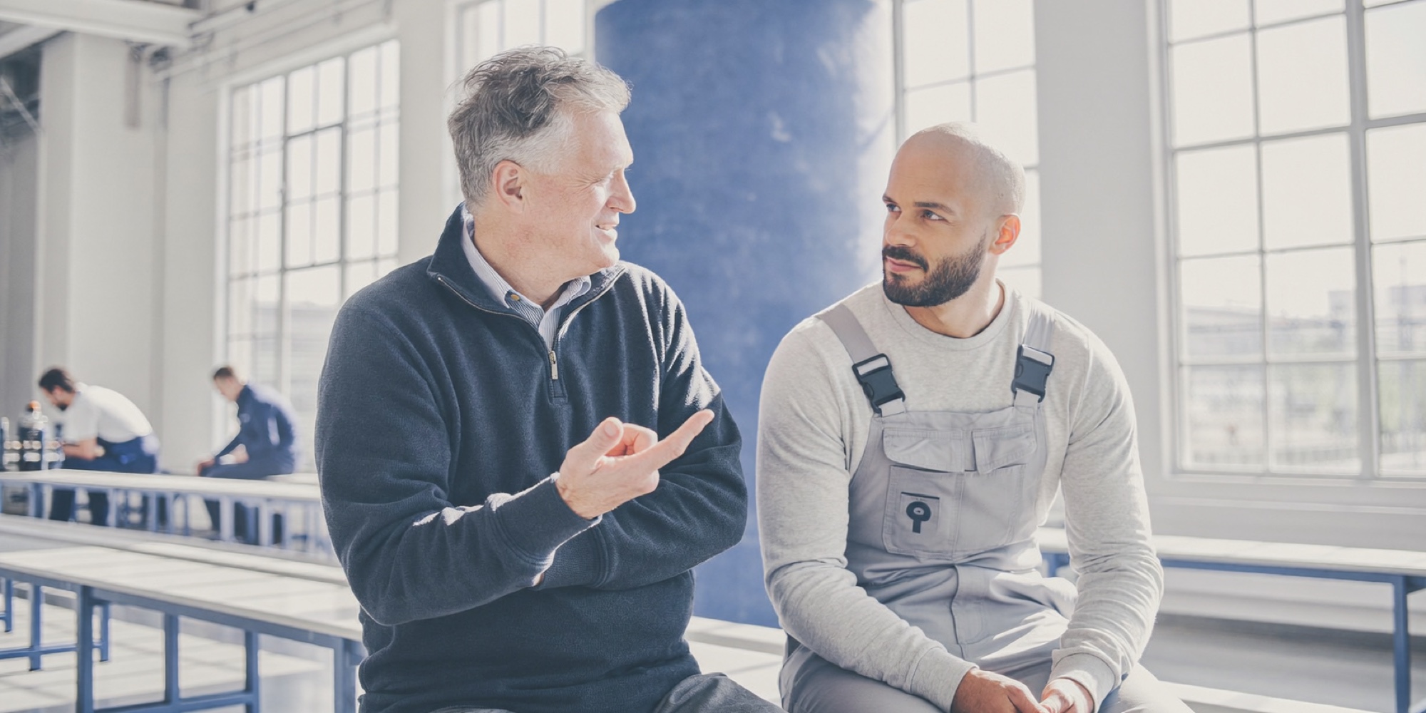 A production manager talking a problem through with a machinist on the plant floor