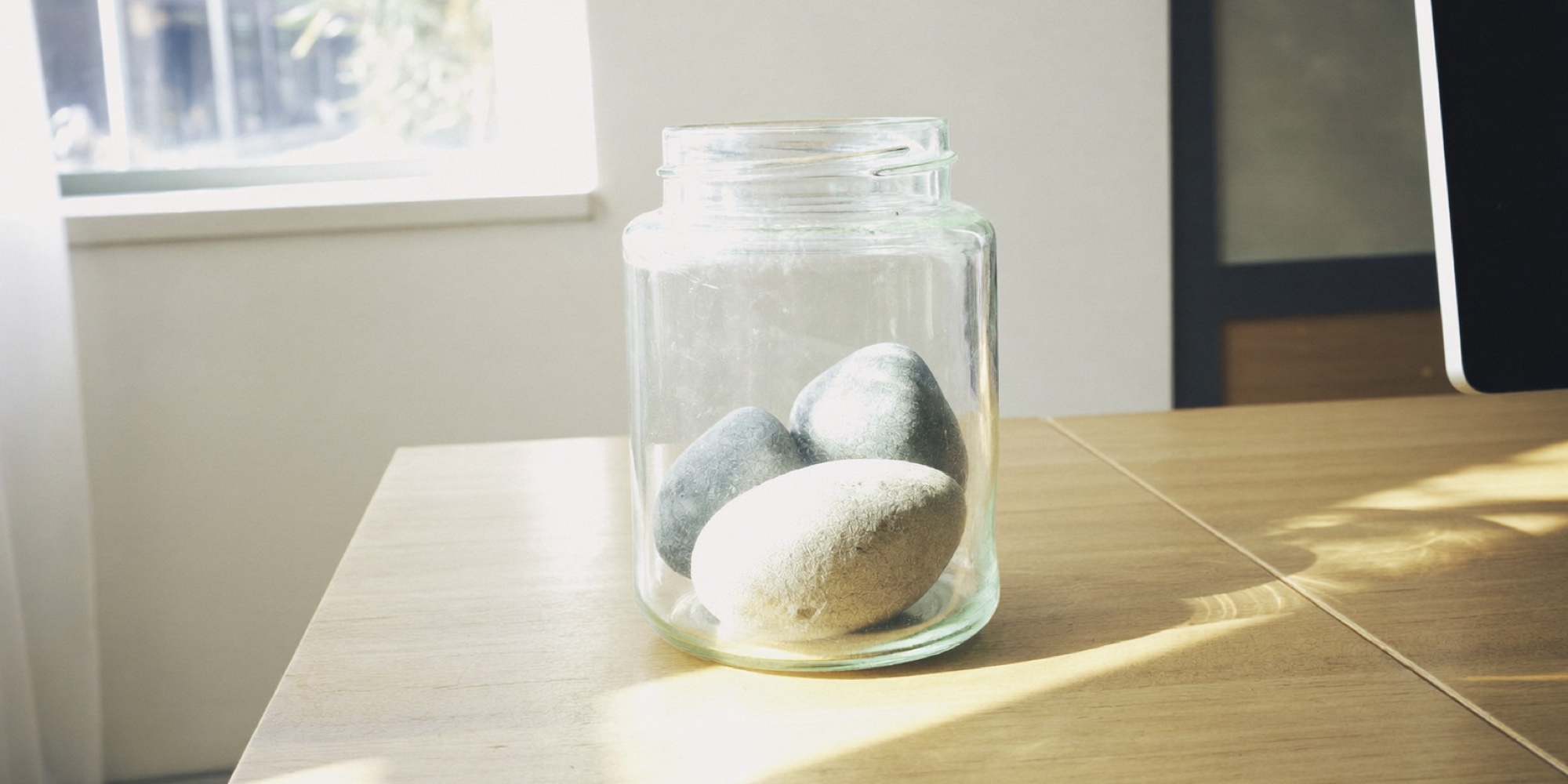 A glass jar with three large stones in it, the big rocks that go into the week before anything else