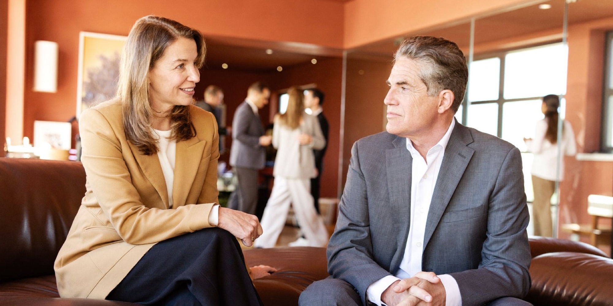 An owner in her fifties talking through the sale of her business with a broker in his office