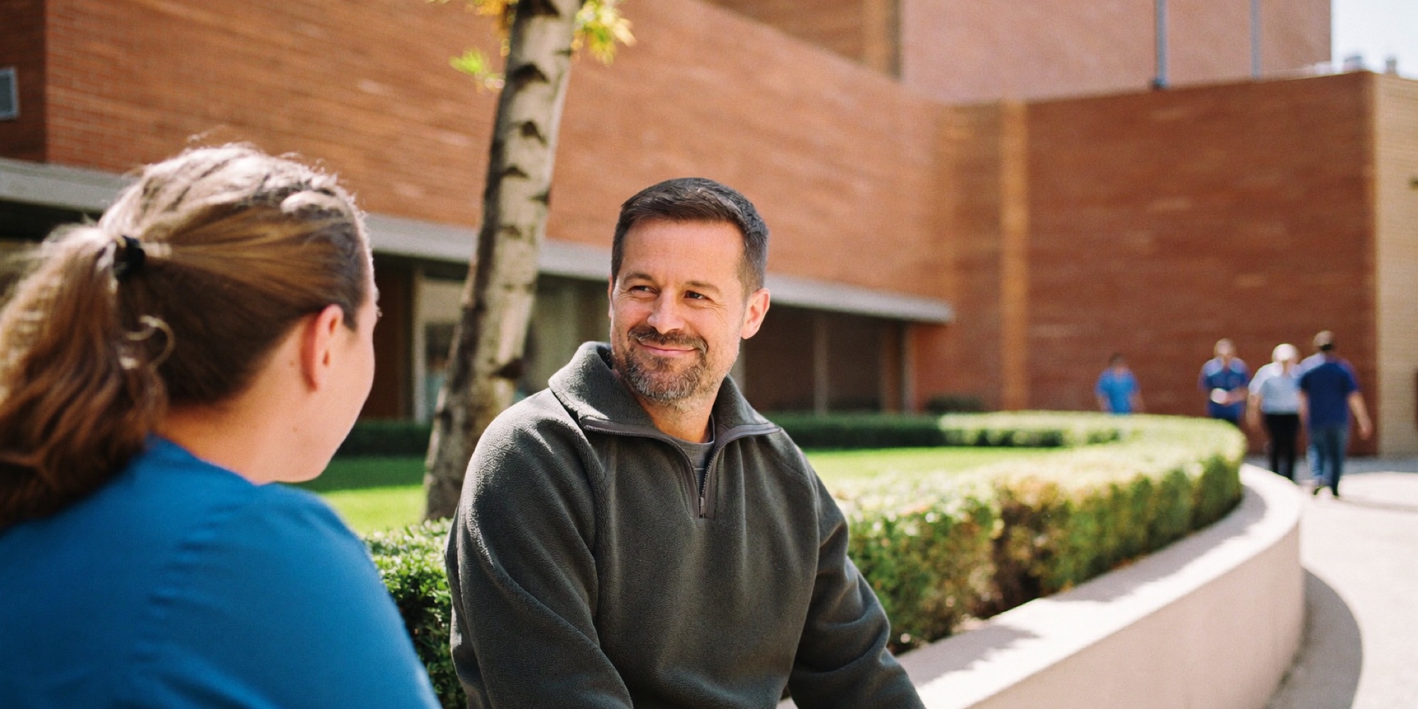 Two hospital colleagues on a break in a courtyard, where the hard conversations are rehearsed before they are needed