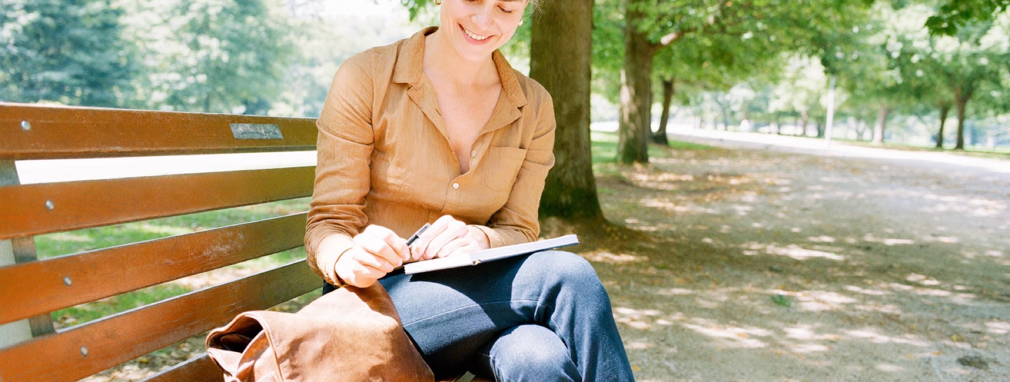 A woman about to review her notes on a park bench the same day