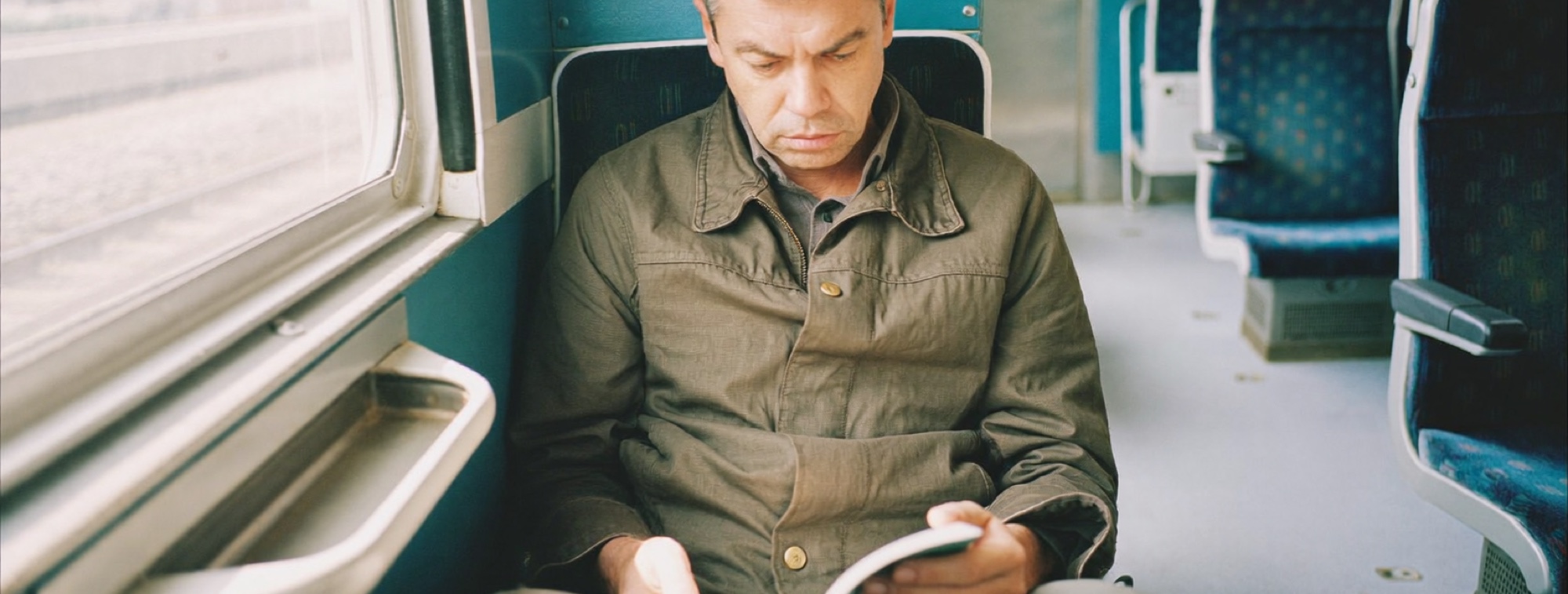 A commuter reading on a morning train, the second pass through a book