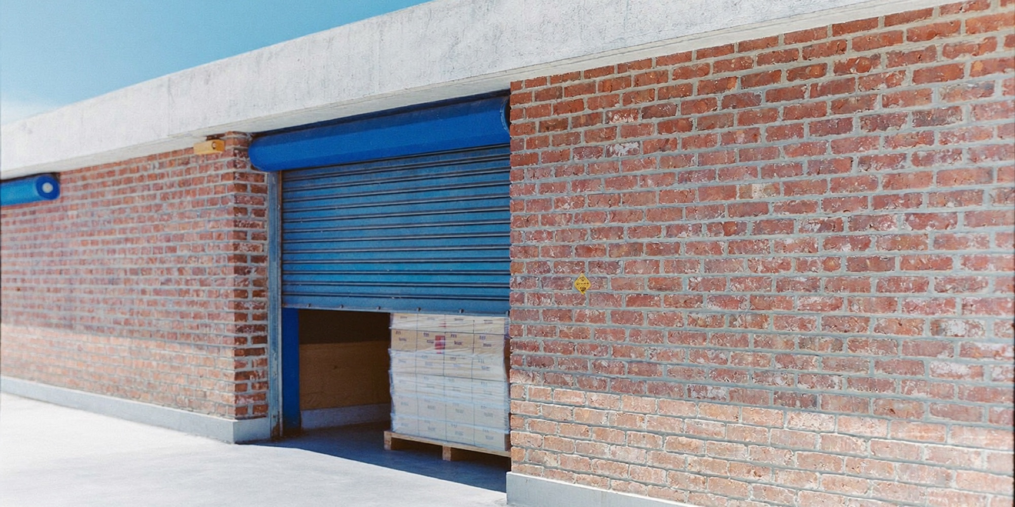 The brick frontage of a small industrial unit with its roller door open, the kind of premises a buyer values on the lease as much as the stock
